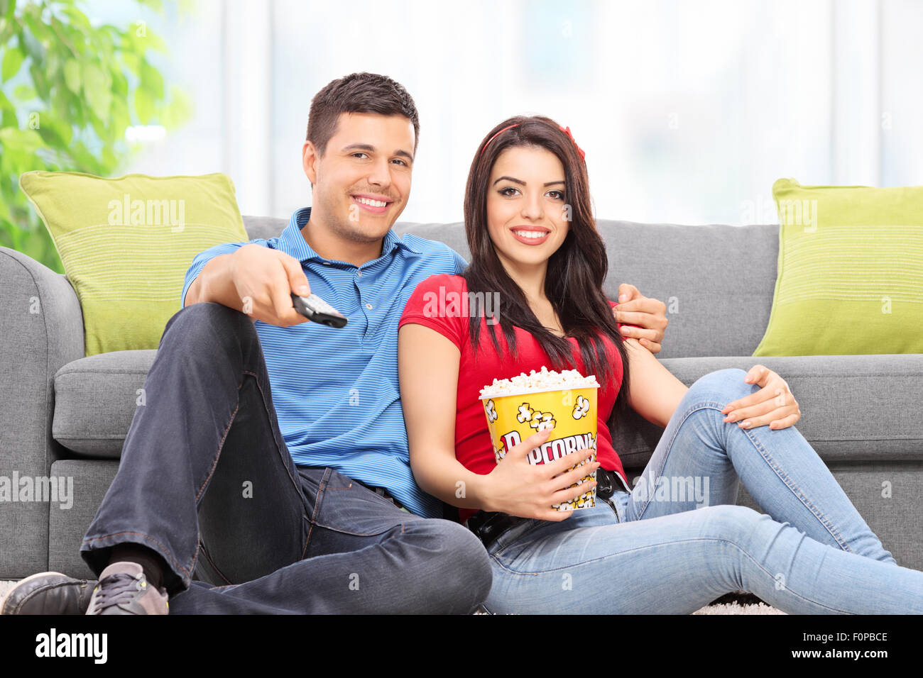 Junges Paar vor dem Fernseher sitzen auf dem Boden zu Hause Stockfoto