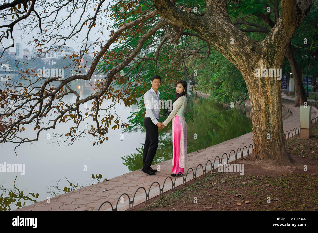 Romantische asiatische Paar, eine junge vietnamesische Paar hält Hände für ein Foto neben Hoan Kiem Lake in Hanoi, Vietnam darstellen. Stockfoto