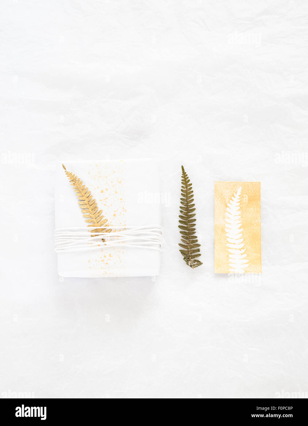 einfach Weihnachten Geschenkpapier in weiß und Gold weißes Seidenpapier mit Goldfarbe spritzte verziert mit Farn gemalt gold Stockfoto