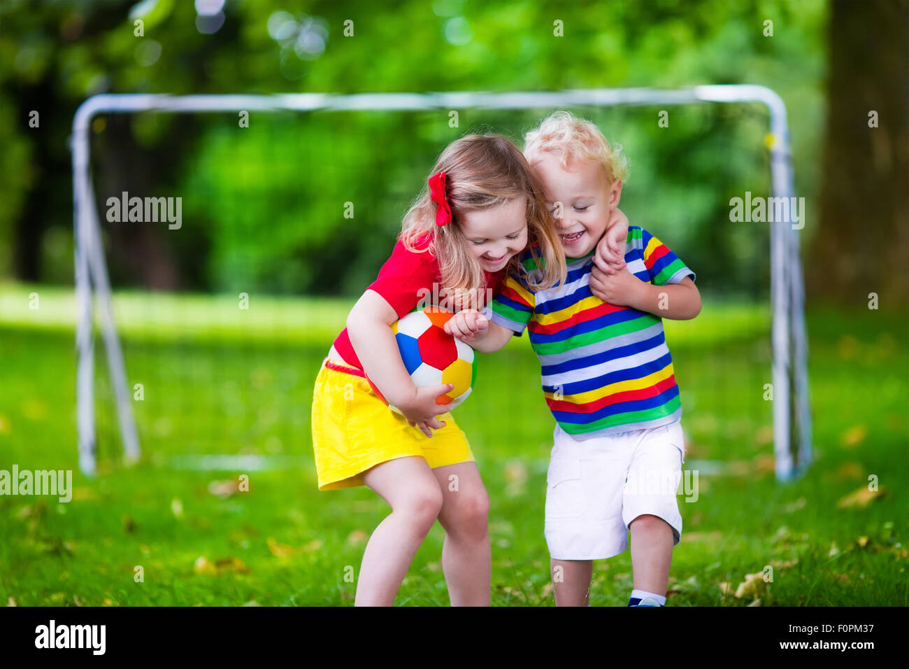 Zwei glückliche Kinder spielen Fußball im Freien im Schulhof. Kinder spielen Fußball. Aktiv Sport für Vorschulkind Stockfoto