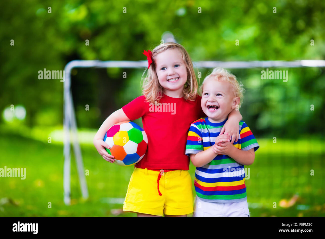 Zwei glückliche Kinder spielen Fußball im Freien im Schulhof. Kinder spielen Fußball. Aktiv Sport für Vorschulkind Stockfoto