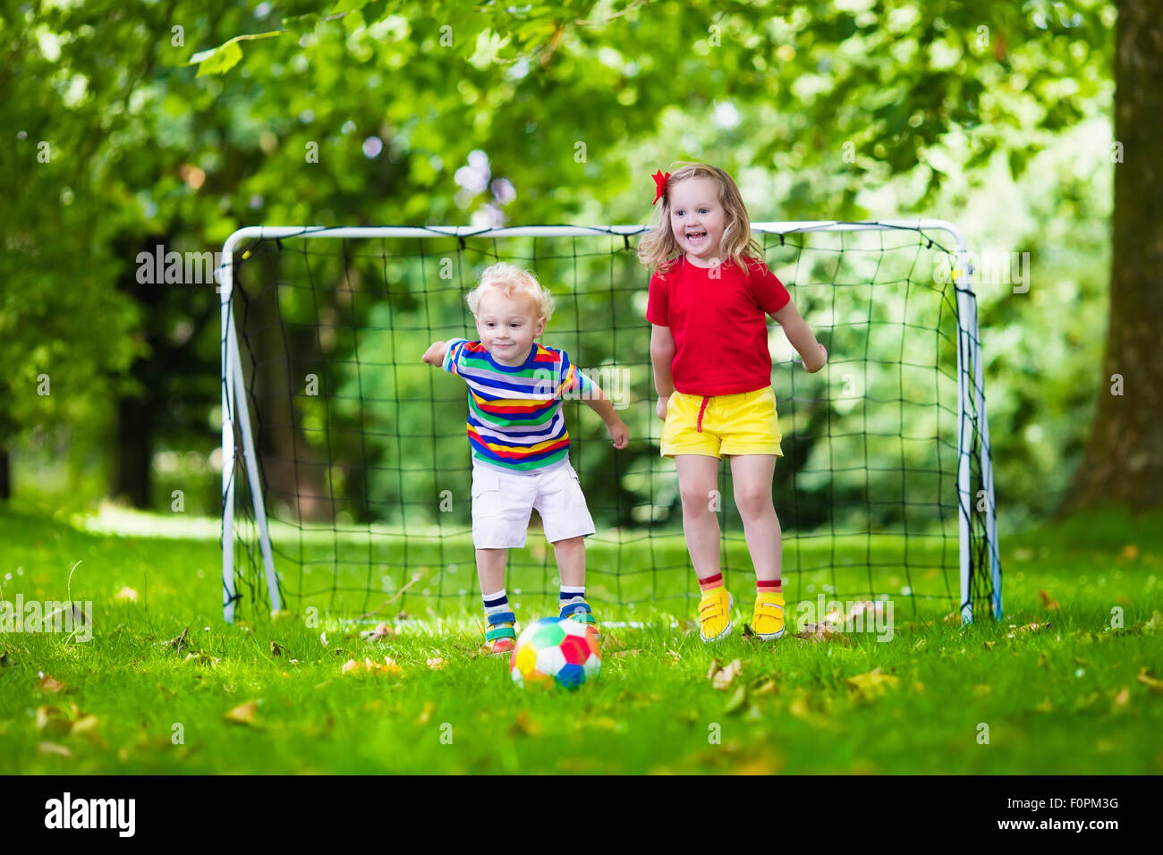Zwei glückliche Kinder spielen Fußball im Freien im Schulhof. Kinder spielen Fußball. Aktiv Sport für Vorschulkind. Stockfoto