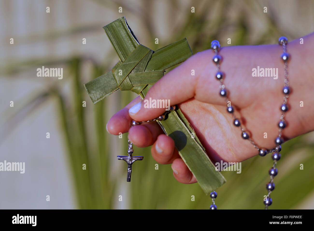 Einzelne Hand hält ein Kreuz und Rosenkranz Perlen Stockfoto