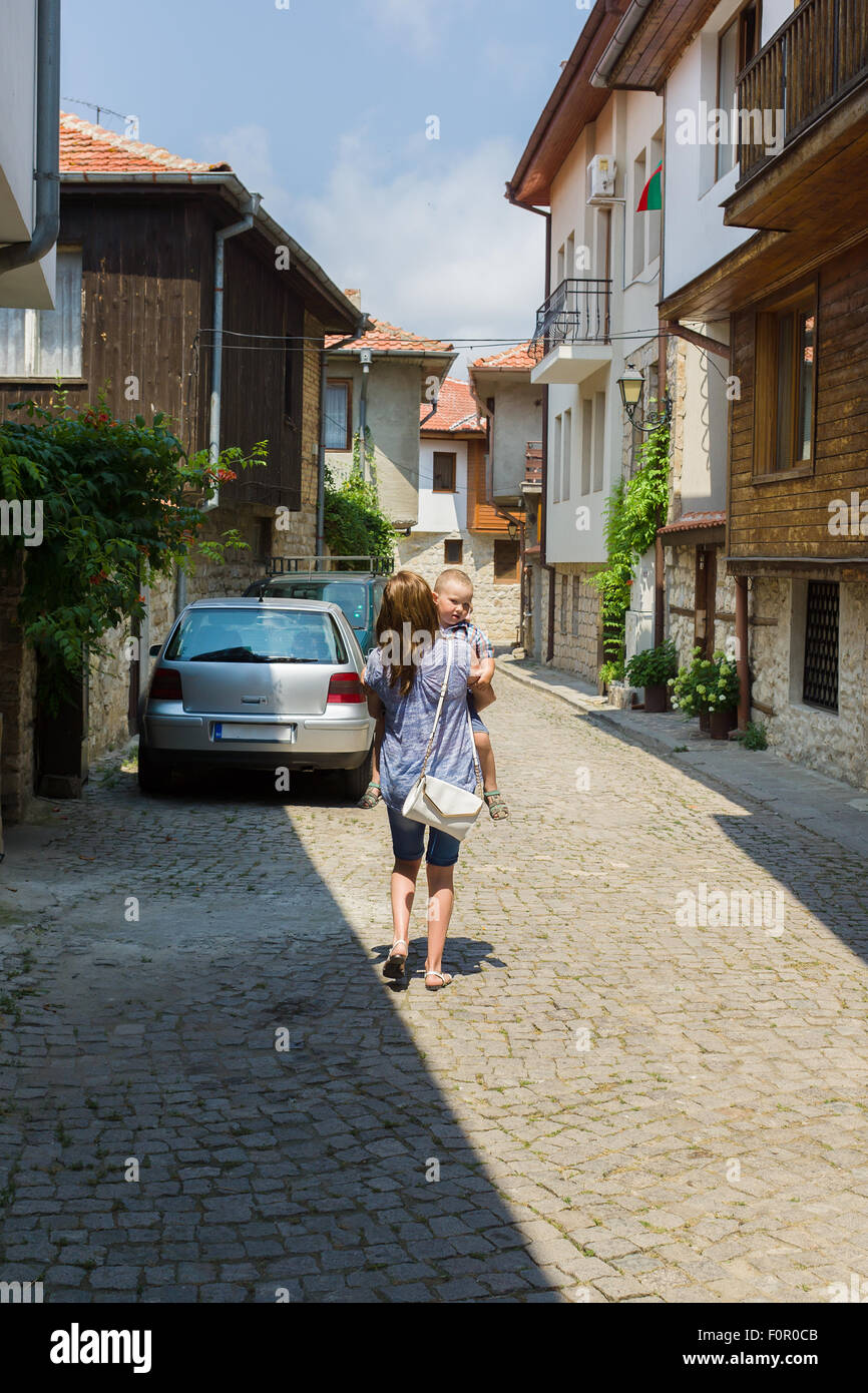 Mutter trägt das müde Kind auf Händen auf kleine Gassen Stockfoto