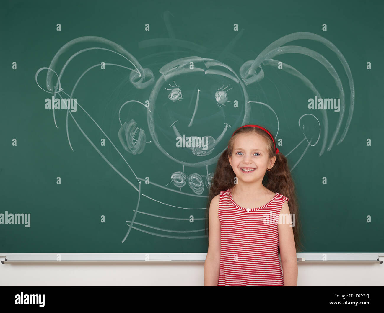 Mädchen Zeichnung Gesichter auf das Schule-Brett Stockfoto