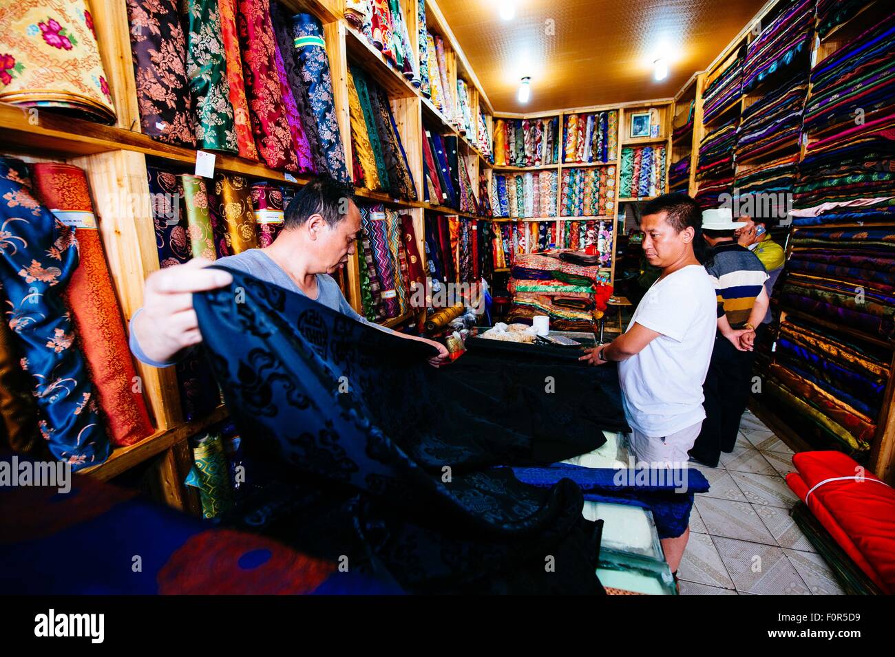 Lhasa, China Tibet autonome Region. 16. August 2015. Genqoi Tashi wählt Stoff für seine Entwürfe in Lhasa, der Hauptstadt von Südwesten Chinas Tibet autonome Region, 16. August 2015. Genqoi Tashi, 32, etablierte seine eigene Modemarke Yeeom, verbindet traditionellen Kultur der tibetischen Volksgruppe und moderne Mode, im Jahr 2012. Genqoi Tashi hat die Modemarke Yeeom bekannt weltweit und nimmt Aufträge aus Indien, Nepal und europäischen Ländern. © Liu schönes/Xinhua/Alamy Live-Nachrichten Stockfoto