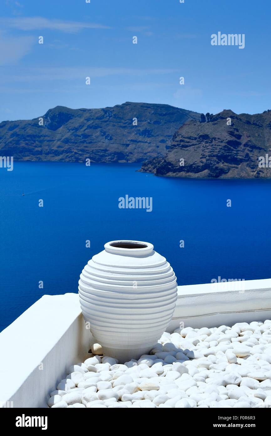 Ein gerippter Outdoor-Pflanzer auf einem Bett aus Kieselsteinen mit einem blauen Meer Hintergrund weiß lackiert. Santorini Griechenland Stockfoto