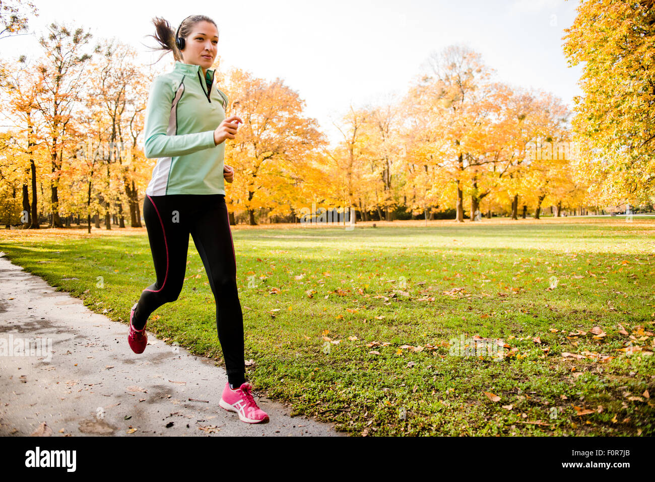 Junge Frau mit Kopfhörern laufen im Herbst Natur und Musik hören Stockfoto