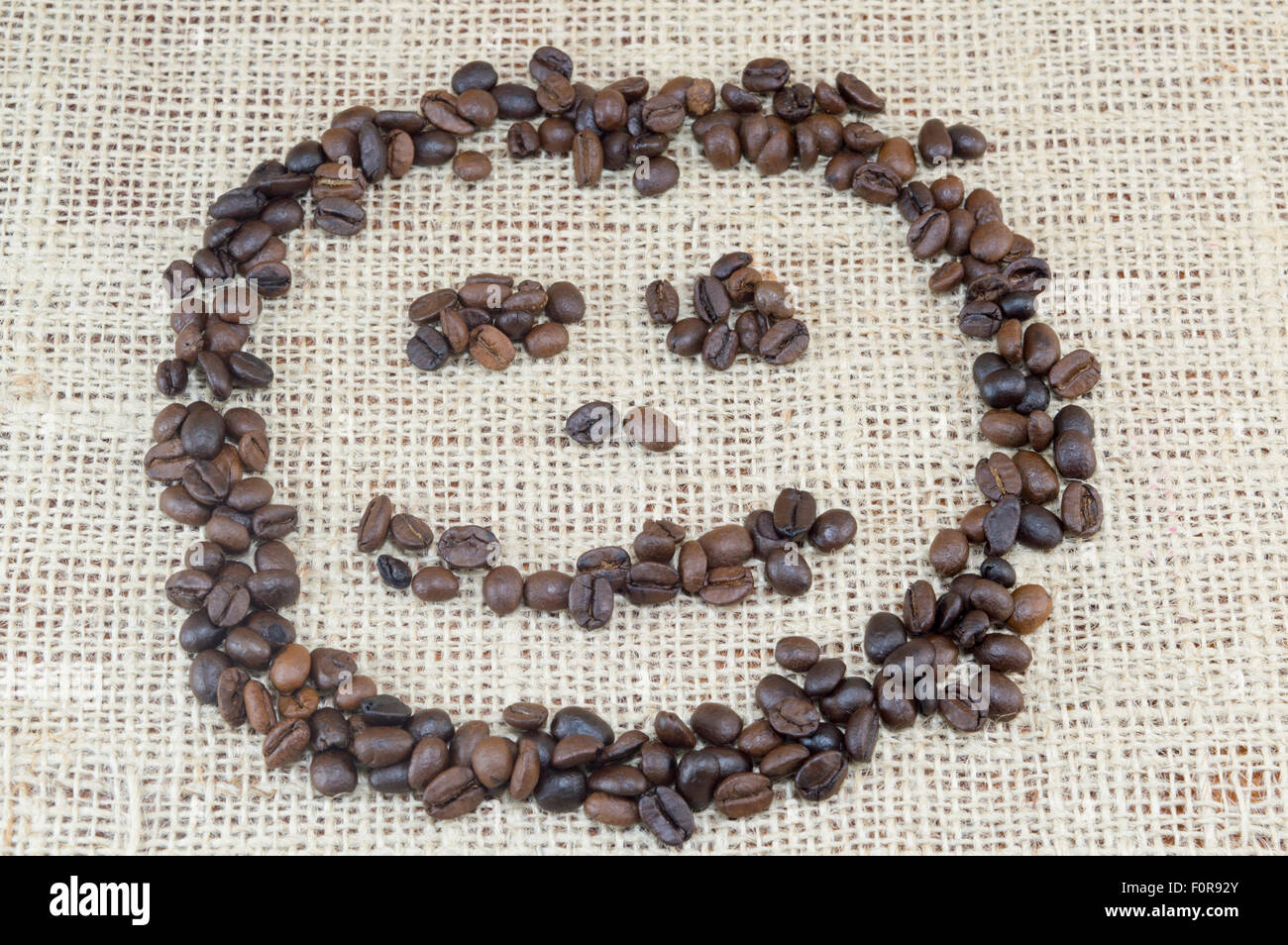 Smiley-Gesicht, hergestellt ausschließlich aus Kaffeekörner auf Kaffee Tasche Textur gelegt Stockfoto