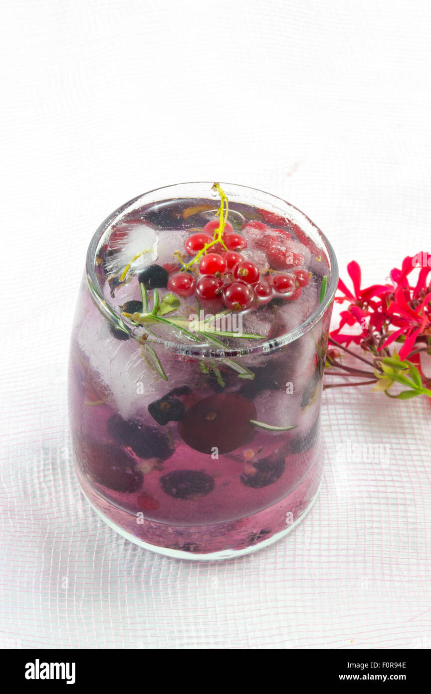 Naturwald hausgemachte rote Frucht Cocktail mit Eis, Zitrone in Scheiben und geschnittene Früchte in einem krummen Glas kaltes Getränk Stockfoto