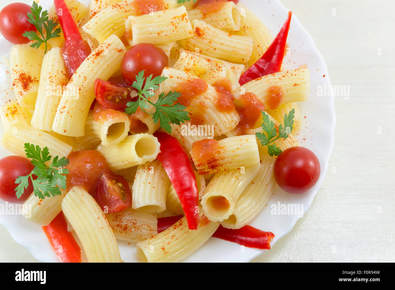 Makkaroni mit Cherry-Tomaten, Petersilie und Paprika serviert mit einer Tomaten-Sauce-Nahaufnahme Stockfoto