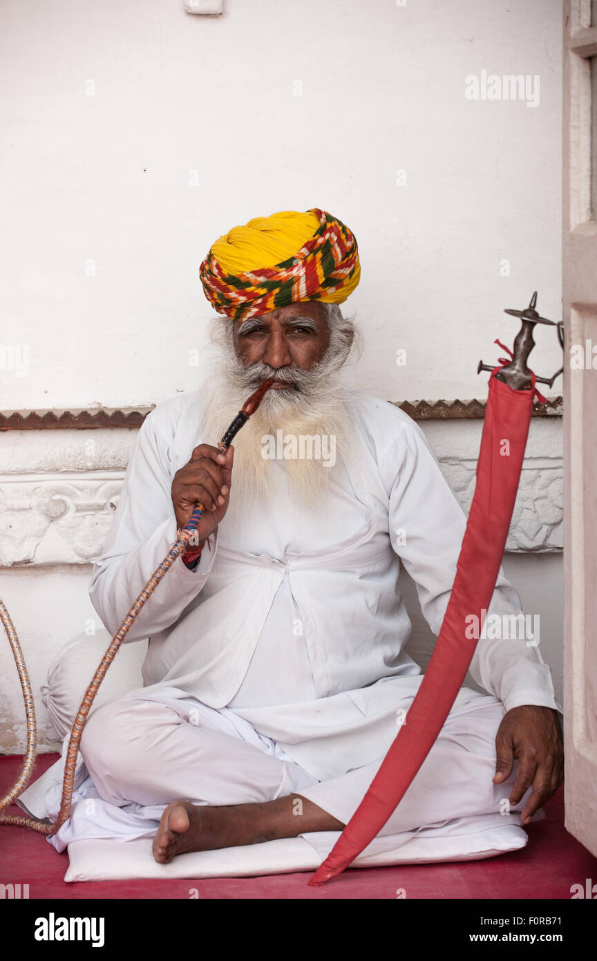 Jodhpur, Indien. Mehrangarh Sandstein Wallburg der Marwar Herrscher. Ein Mann in traditioneller Kleidung eine Shisha Wasserpfeife. Stockfoto