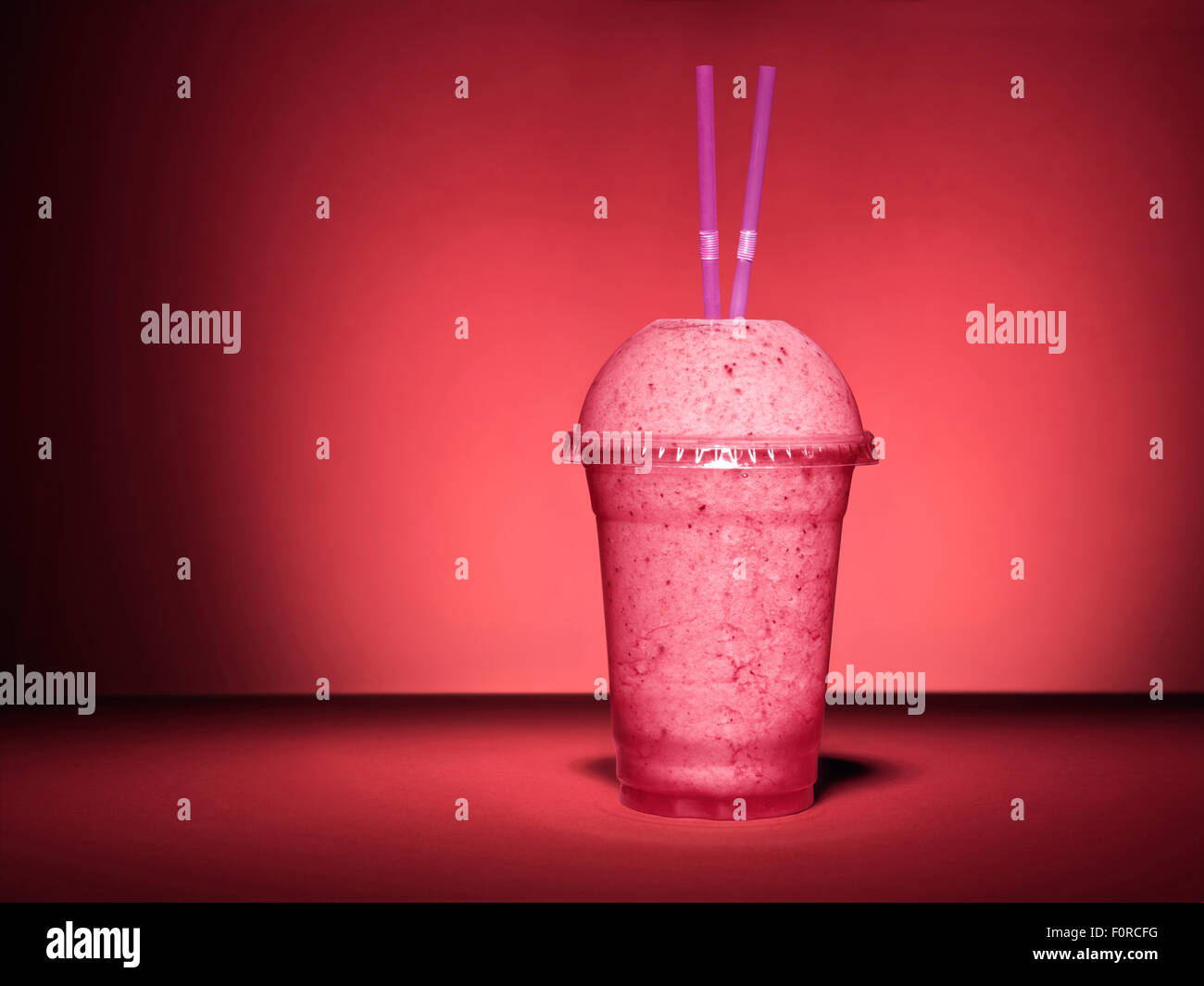 Schuss von einen einzigen, rosa, Frucht-Smoothie auf einem roten vielfarbig Hintergrund mit textfreiraum für den Designer. Stockfoto