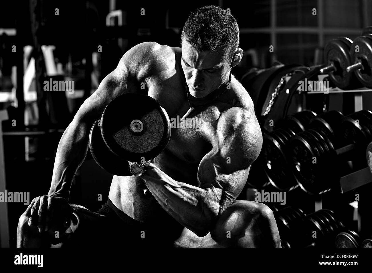 sehr athletischen Kerl Bodybuilder macht, Übung mit Hanteln, in dunklen Turnhalle, schwarz / weiß Foto ausführen Stockfoto