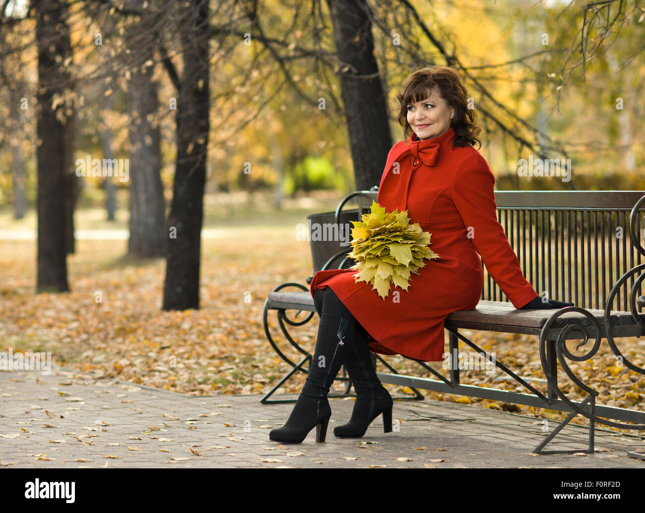 Die Reife schöne Frau im roten Mantel, outdoor im Park, Herbsttag Stockfoto