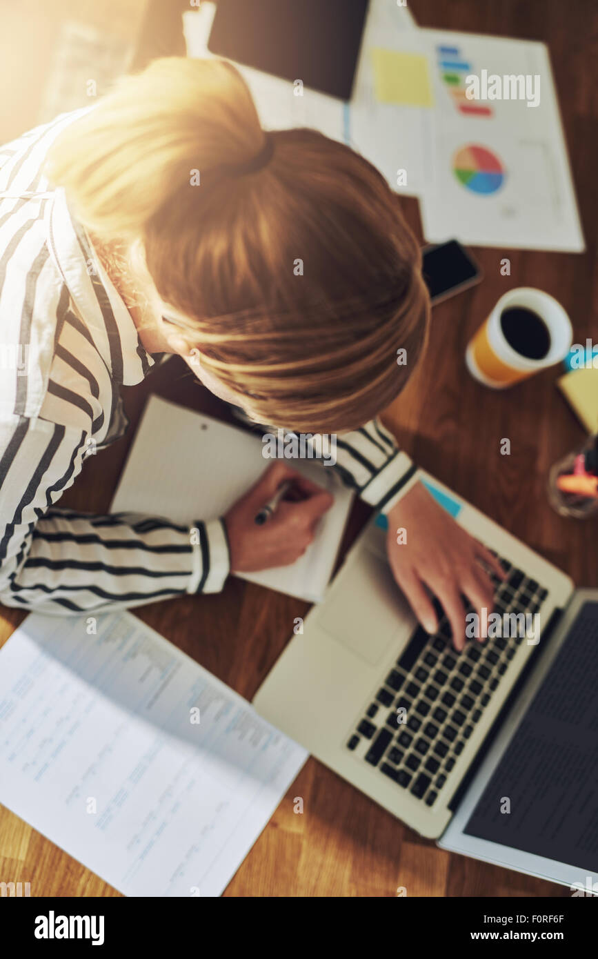 Fleißige erfolgreiche weibliche Unternehmer arbeiten an ihrem Schreibtisch in Ihrem Büro zu Hause schreiben, da sie neue Märkte auf Forschungen Stockfoto
