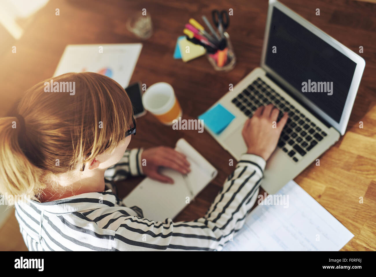 Junge Unternehmerin arbeiten sitzen an einem Schreibtisch, tippen auf ihren Laptop-Computer in einem Büro zu Hause, Ansicht von oben Stockfoto