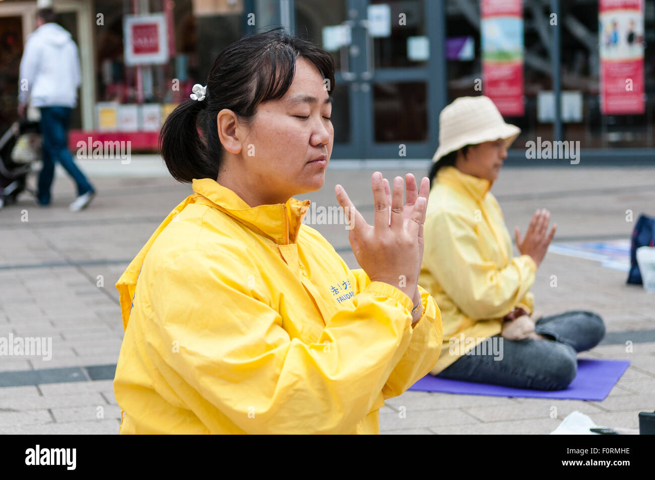 Zwei chinesische Frauen üben Falun Gong (Dafa) in einer belebten Innenstadt Stockfoto