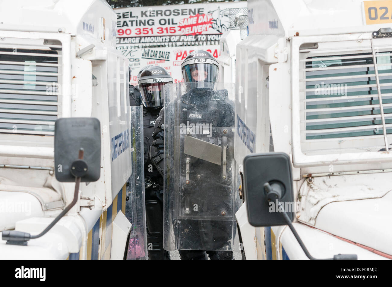 PSNI Polizisten gekleidet in schützende Riot Gear Stand hinter gepanzerten Landrover mit Schilden Stockfoto