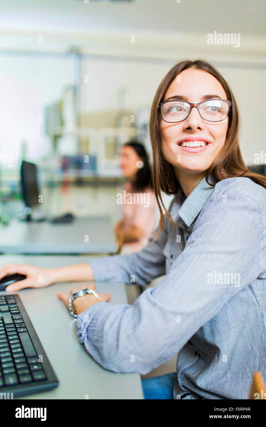 Junge schöne Mädchen, die an einem Computer in einem Klassenzimmer arbeiten Stockfoto
