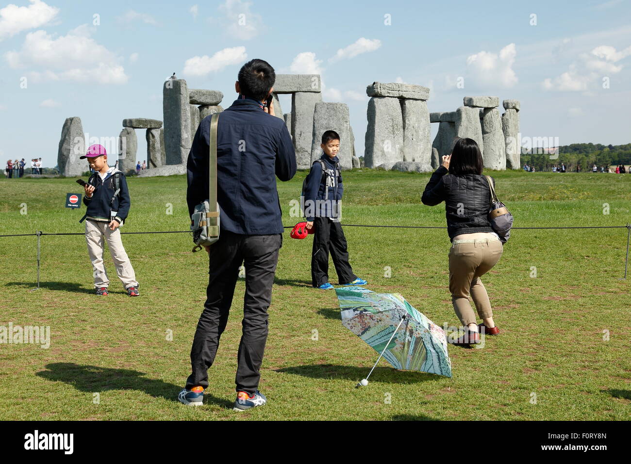 Eine Familie von asiatischen Touristen den Steinkreis von Stonehenge bei Salisbury Plain, England UK anzeigen Die Mutter nimmt ein Bild. Stockfoto