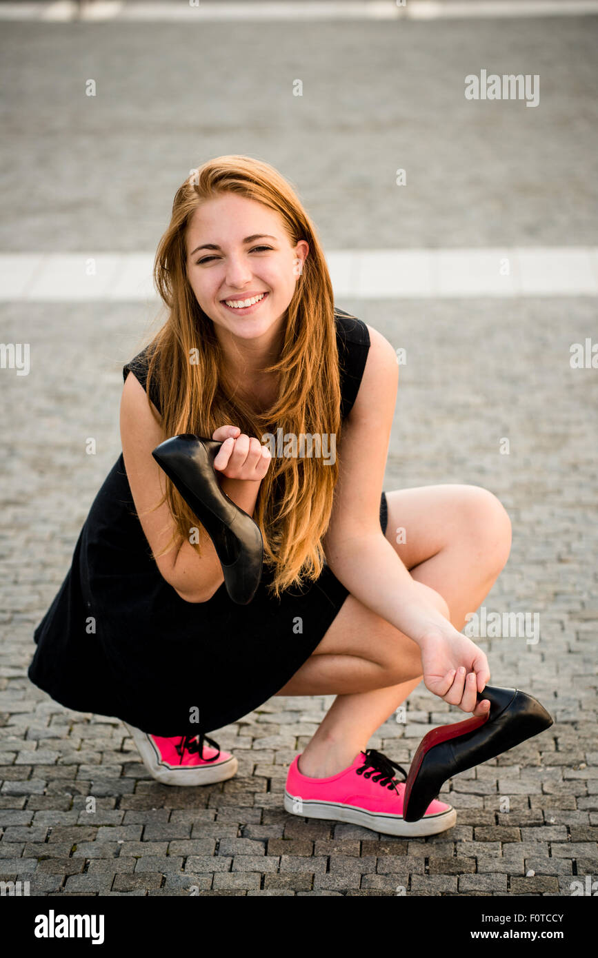 Junge Frau auf der Straße in Turnschuhen mit high Heels Schuhe Stockfoto