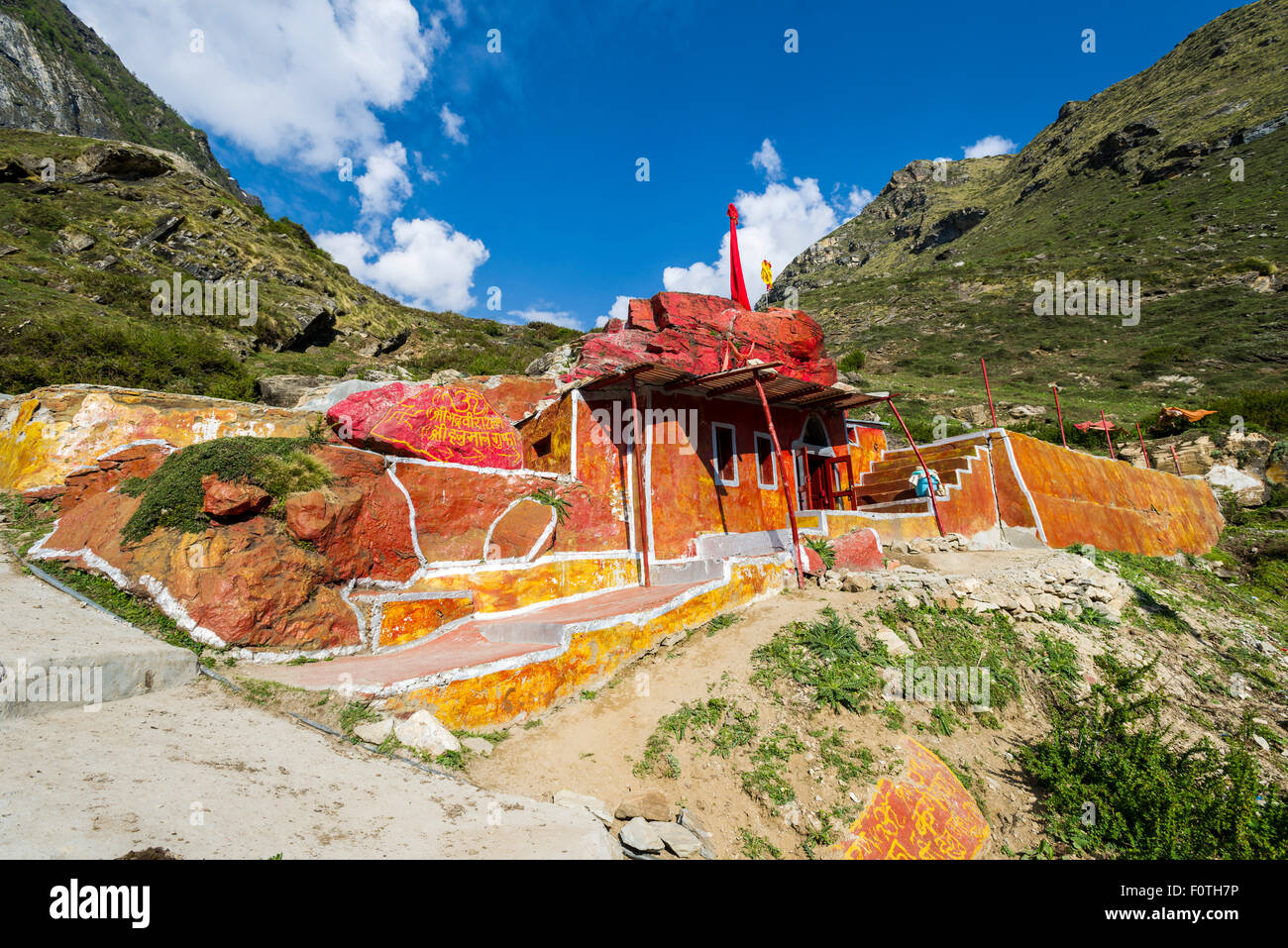 Rot und orange lackierte Höhle Haus ein Sadhu, heiliger Mann, in den Hügeln über der Stadt, Badrinath, Uttarakhand, Indien Stockfoto