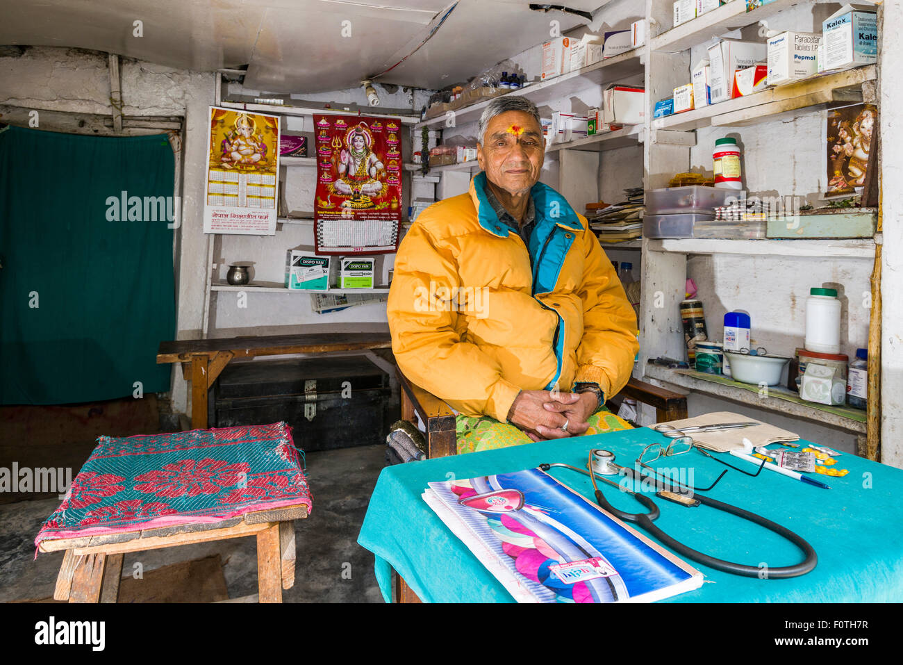Der Arzt sitzt in seiner freien Praxis, Medizin, gespeichert im Regal hinter ihm, Badrinath, Uttarakhand, Indien Stockfoto
