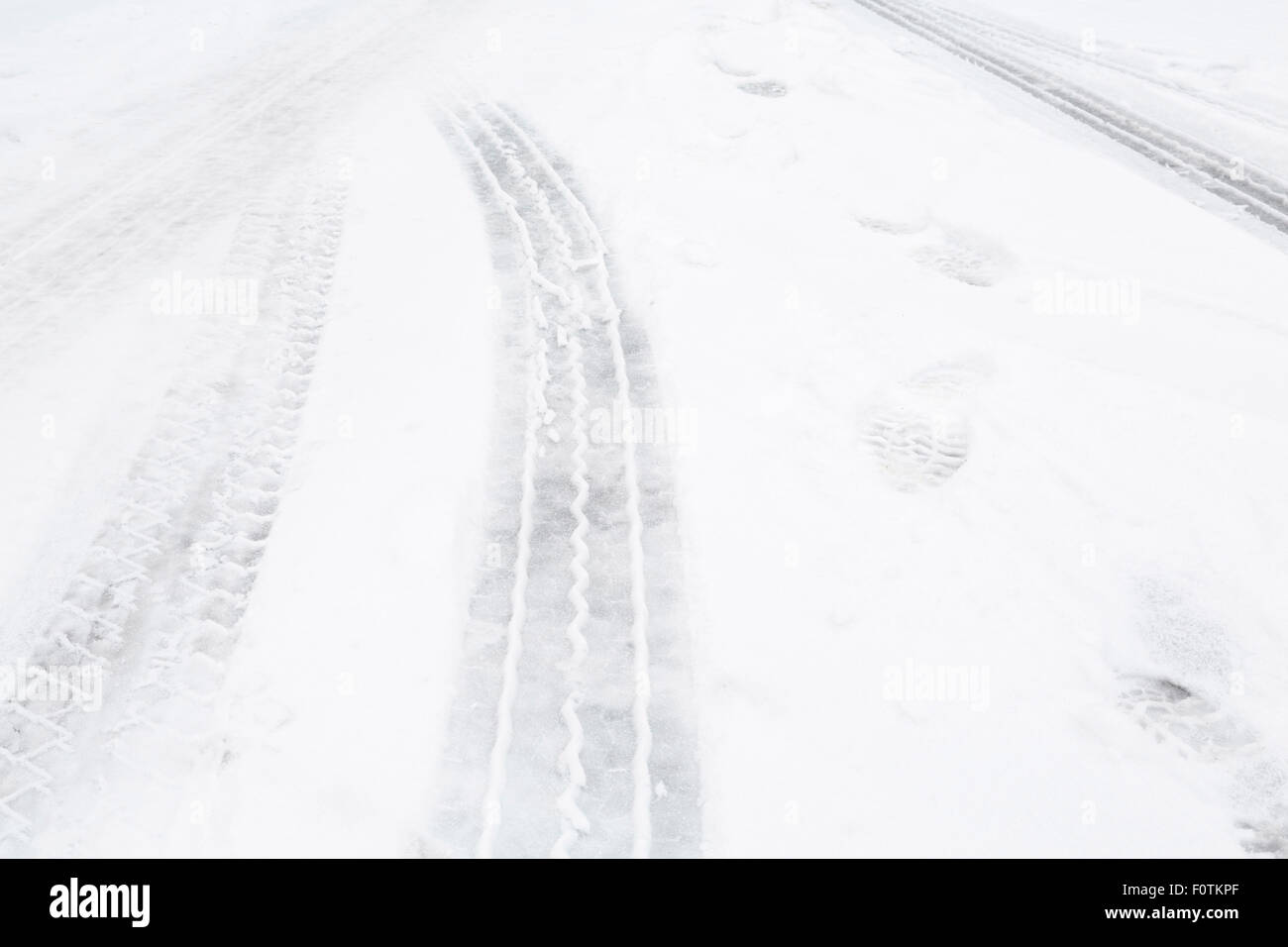 Nahaufnahme von Reifenspuren auf einer Straße mit Schnee Stockfoto