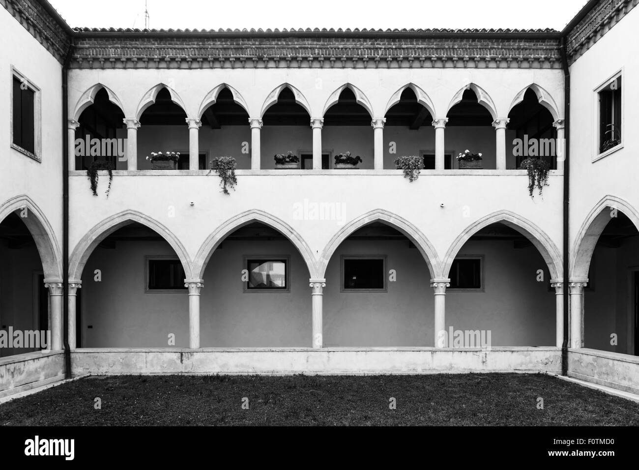 rechteckige Kreuzgang mit gotischen Bögen und Säulen aus Marmor. Im ersten Stock Bögen eine schöne Loggia mit gotischen Kleeblatt. Stockfoto