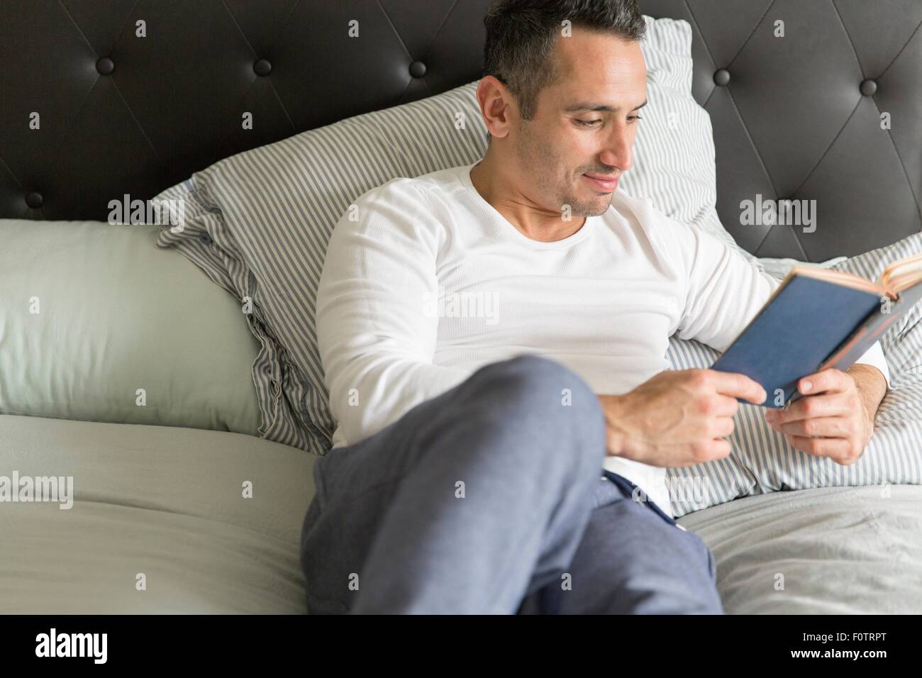 Mitte Erwachsener entspannend Mann, auf Bett, Buch lesen Stockfoto