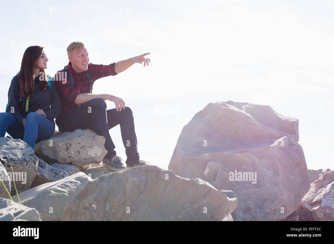 Junges Paar sitzt auf Felsen suchen Weg zeigen Stockfoto