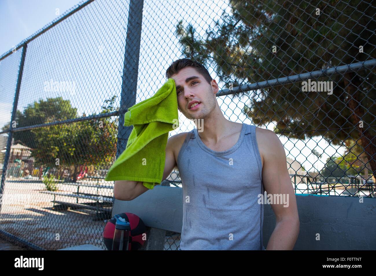 Junge männliche Basketballspieler, wischte sich die Stirn mit Handtuch Stockfoto