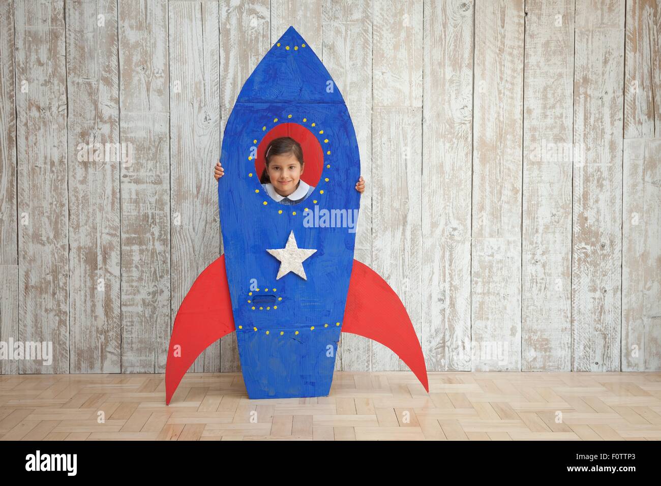 Porträt von Mädchen auf der Suche von Fenster blau hausgemachte Pappe Rakete Stockfoto