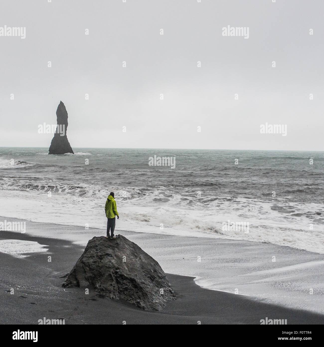 Junge männliche Touristen Blick auf das Meer von Felsformation, Reynisfjara, Island Stockfoto