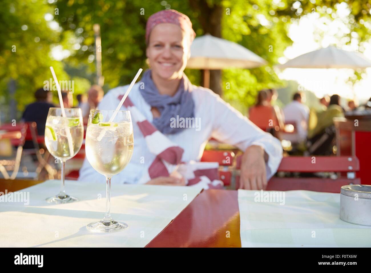 Reife Frau, draußen, sitzen am Tisch mit Getränken Stockfoto