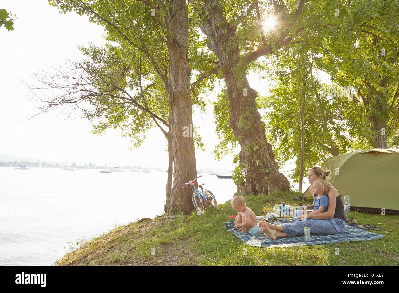 Mutter und Söhne auf der Picknickdecke in ländlicher Umgebung entspannen Stockfoto