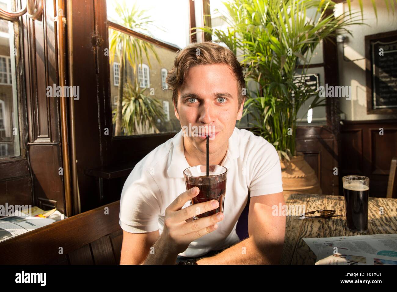 Porträt des jungen Mannes trinken mit Strohhalm, Blick in die Kamera Stockfoto
