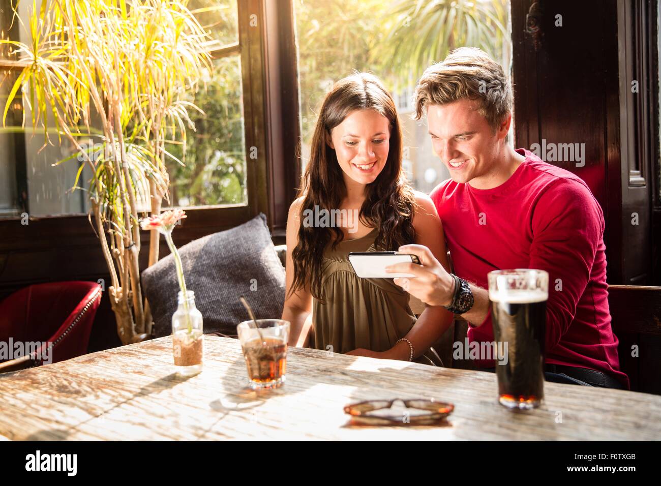 Paar genießt trinkt Blick auf Smartphone zusammen Stockfoto