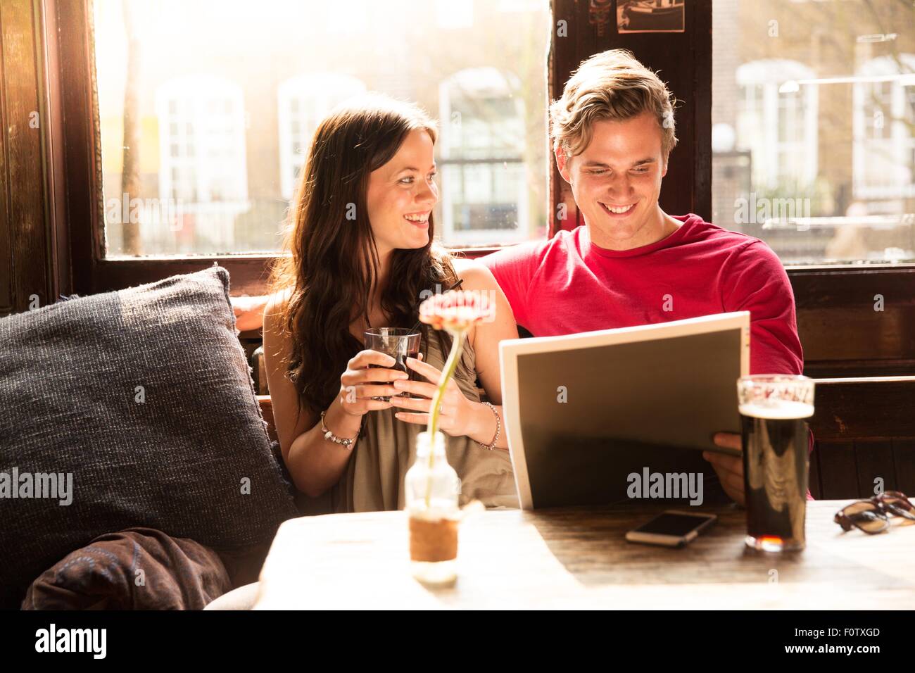 Paar genießt Getränke Zeitung zusammen zu betrachten Stockfoto