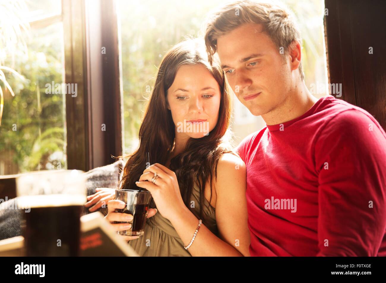 Paar-Sitzung mit einem Drink zusammen lesen Zeitung Stockfoto