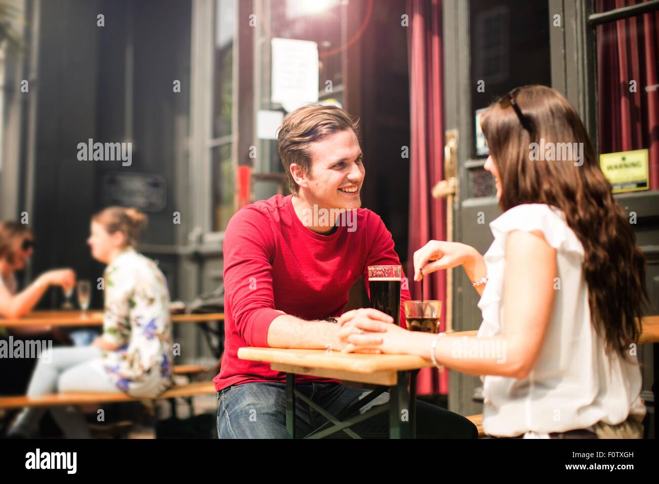 Paar-Sitzung von Angesicht zu Angesicht im Biergarten, die Hand in Hand Stockfoto