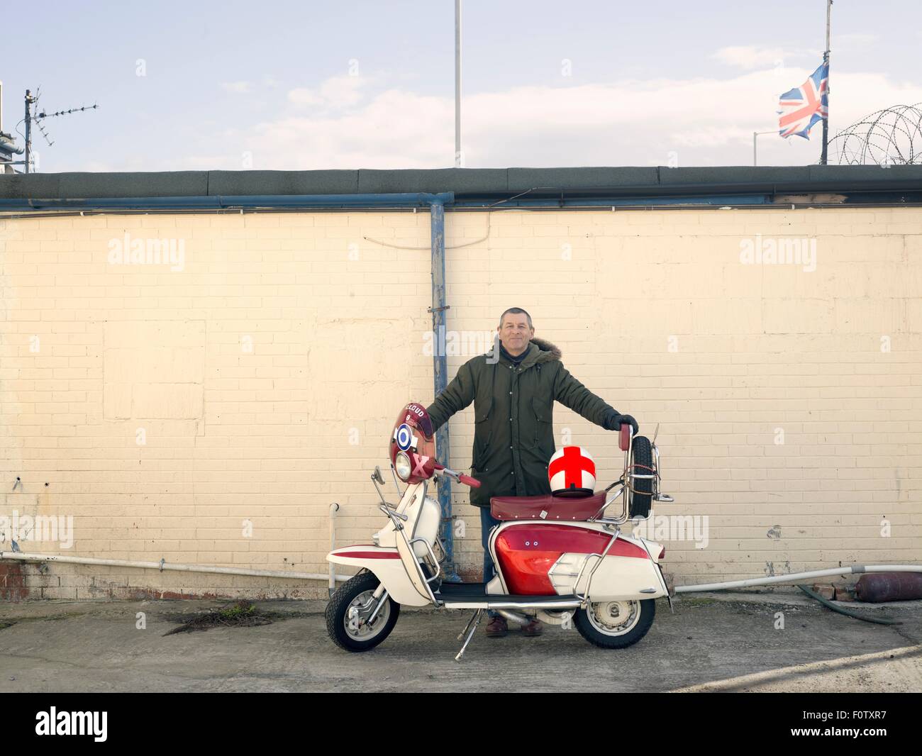 Porträt von Reifen männlichen mod mit Moped vor Wand Stockfoto