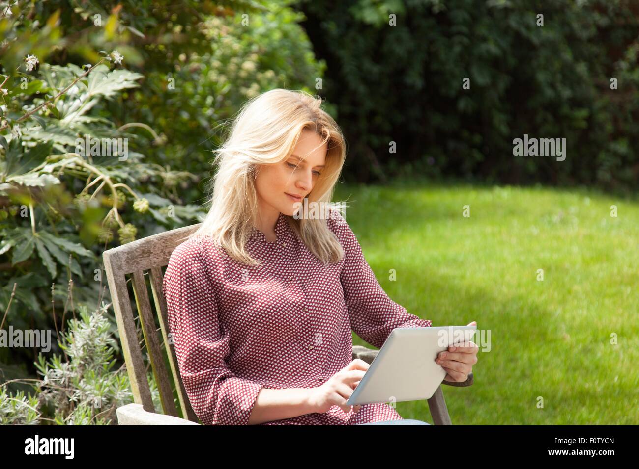 Mitte Erwachsene Frau im Gartenstuhl mit Touchscreen auf digital-Tablette Stockfoto