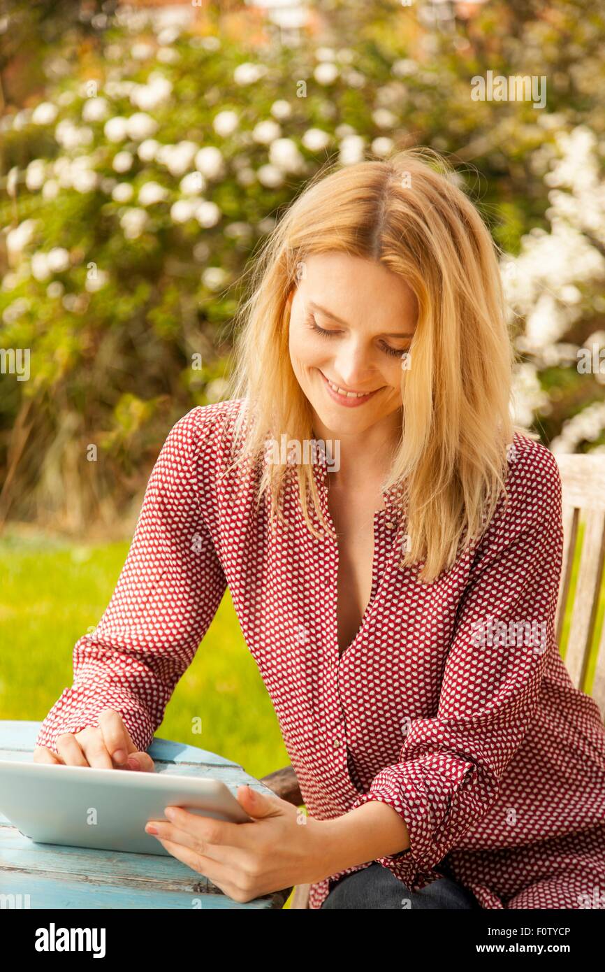 Mitte erwachsenen Frau am Gartentisch mit Touchscreen auf digital-Tablette Stockfoto