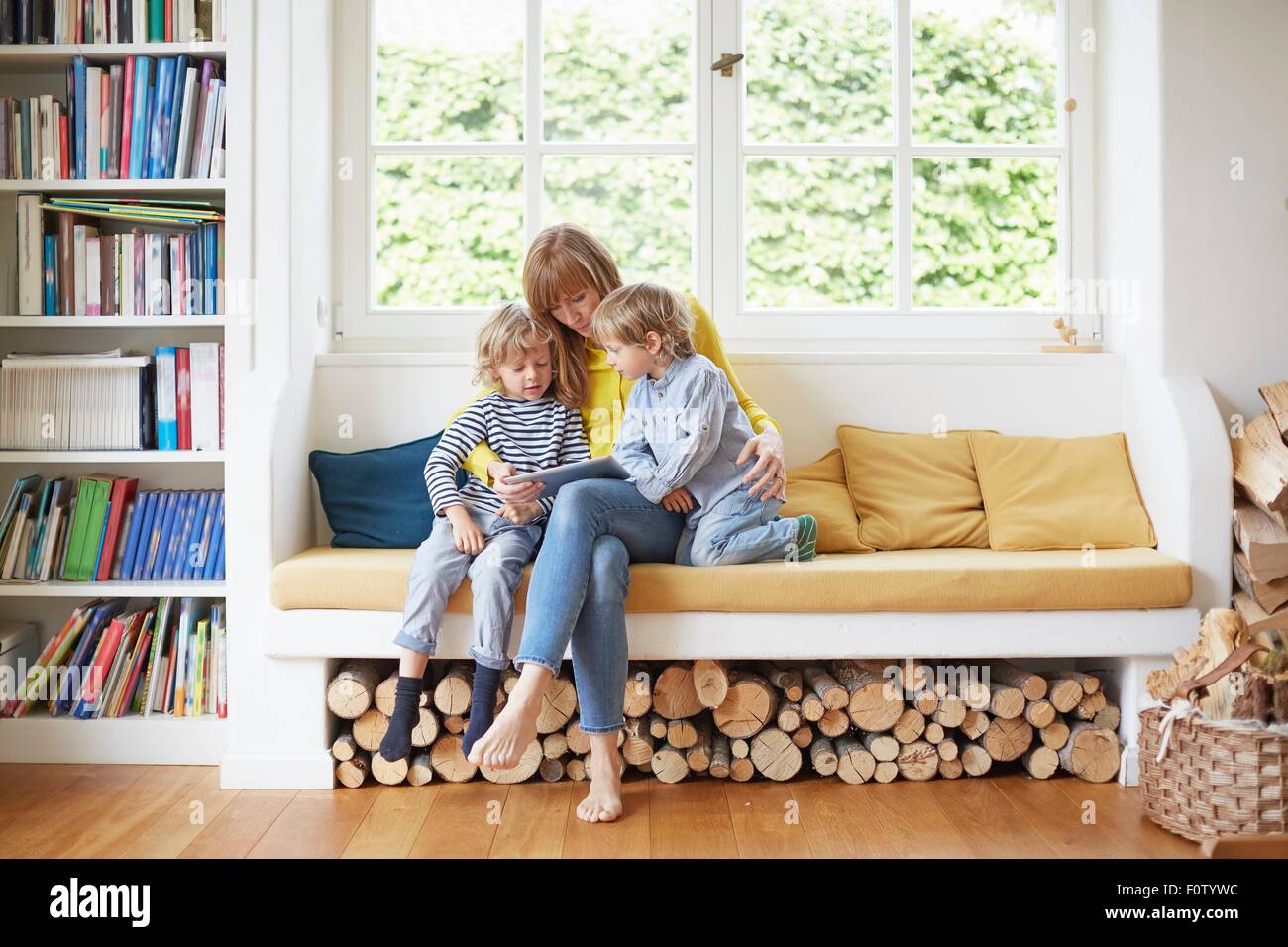 Mutter und zwei Söhne, sitzen in Fensterplatz, Blick auf digital-Tablette Stockfoto