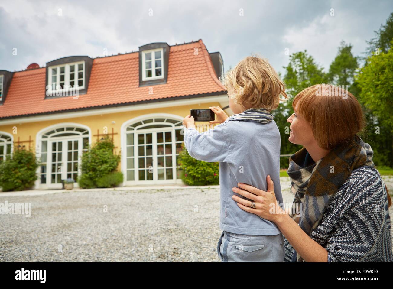 Junge mit Mitte Erwachsene Frau mit Smartphone zum Fotografieren des Hauses Stockfoto