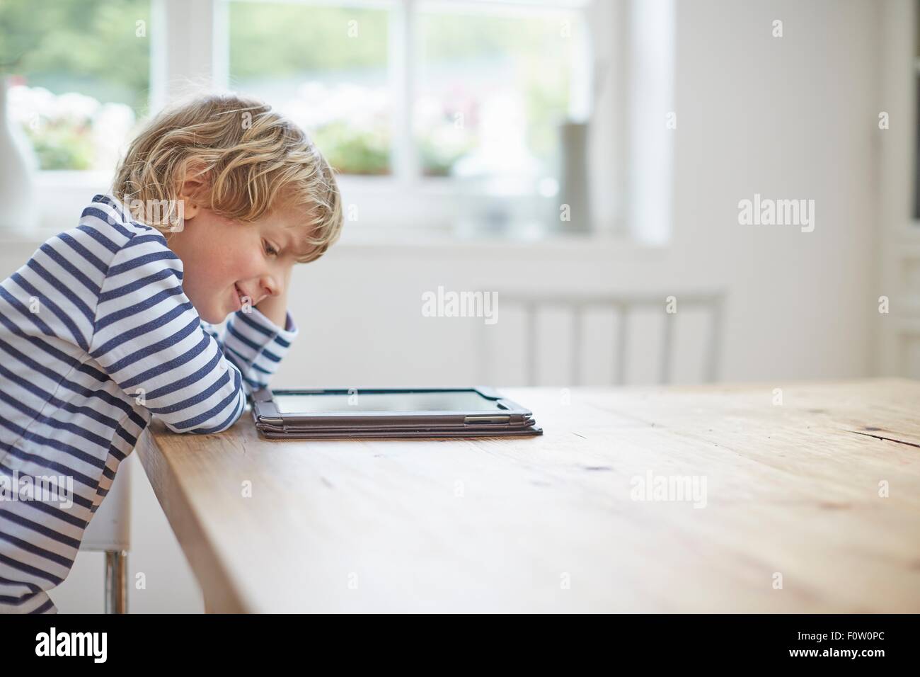 Seitenansicht der Junge sitzt am Tisch, mit digital-Tablette Stockfoto