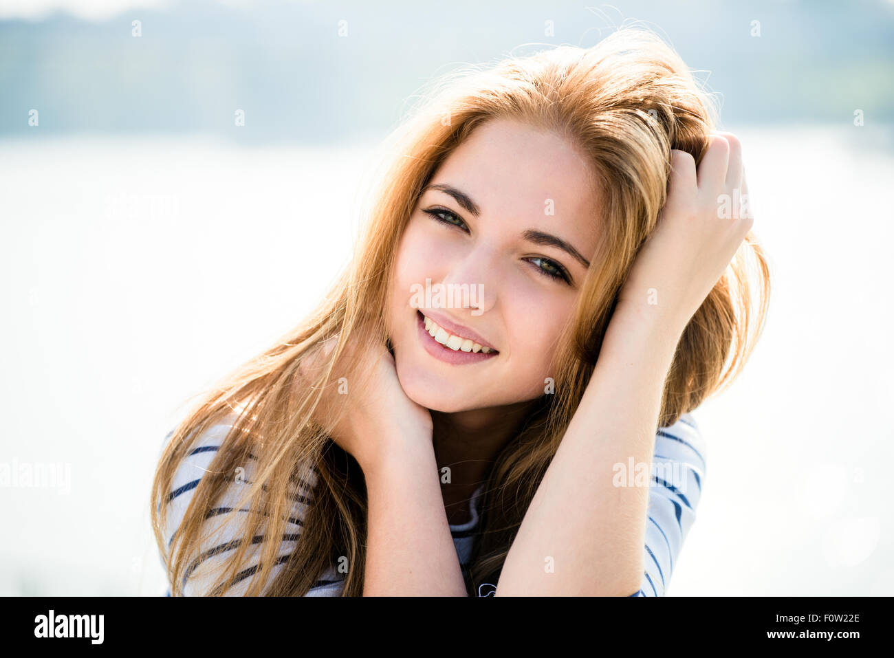 Teenager-Porträt - lächelndes Mädchen im Freien mit Händen in Haar Stockfoto