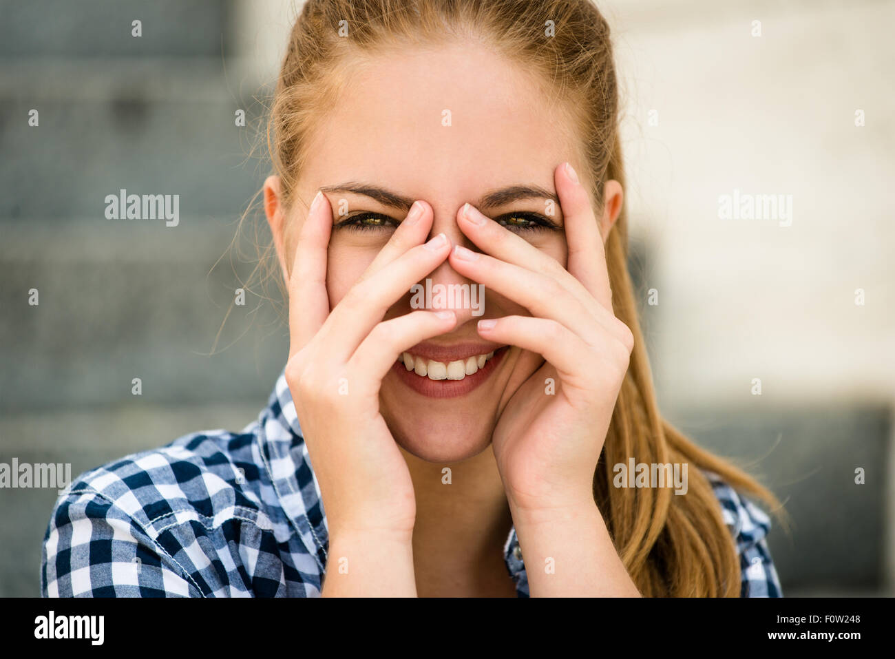 Teenager-Porträt - lächelndes Mädchen im Freien mit Hände vor dem Gesicht Stockfoto